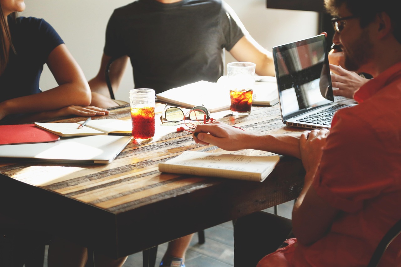 A group exploring ideas with notebooks and a laptop around a table