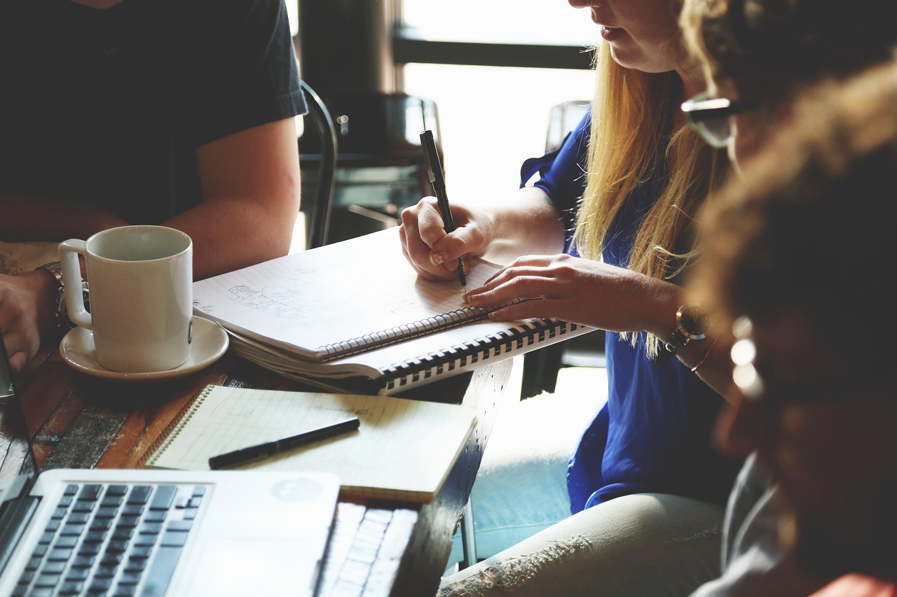 Colleagues listening and taking notes during a conversation